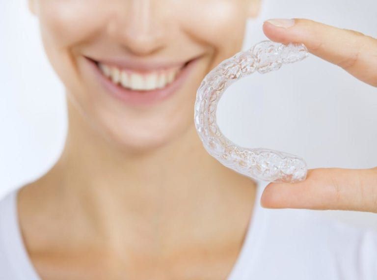 closeup image woman holding clear aligners