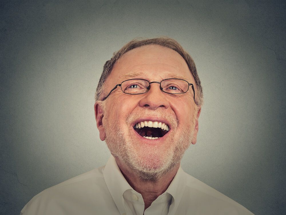 elderly man smiling teeth grey background