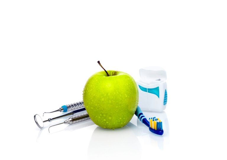 green apple surrounded by dental tools