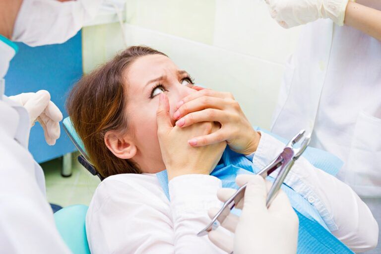 woman holding her mouth in fear of dentist